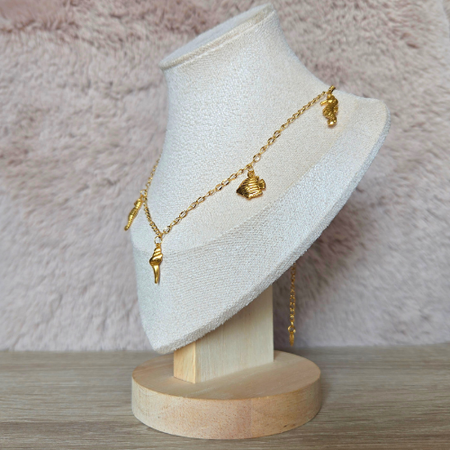 Zomerse goudkleurige ketting met oceaanbedels, close-up zijkant op display.