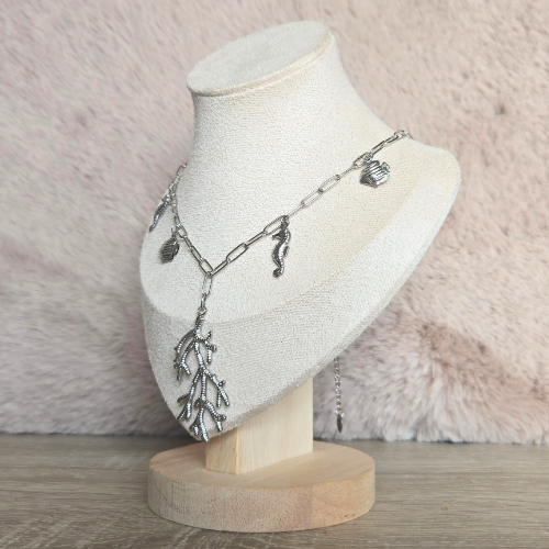 Zijdelingse weergave van een zilverkleurige bedelketting met oceaanbedels op een sieradenstandaard.