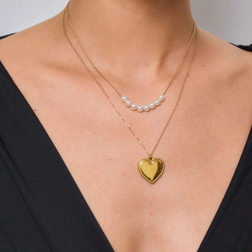 Tweelaagse ketting versierd met parels en een grote hartbedel gedragen om de hals