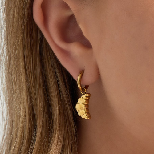 Close-up van oor met de goudkleurige croissant oorbel - gemaakt van hoogwaardig stainless steel