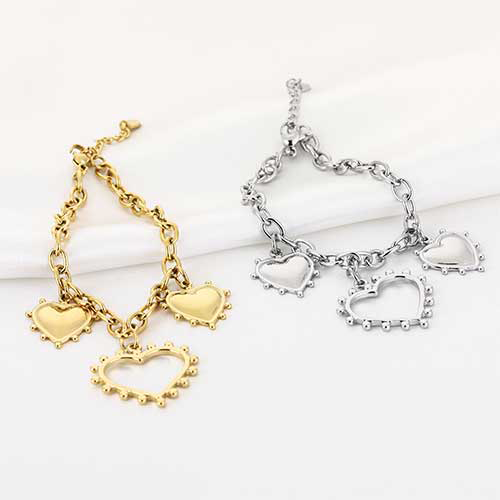 Gouden en zilveren roestvrijstalen schakelarmband met grote hartjesbedels – speelse en romantische uitstraling.
