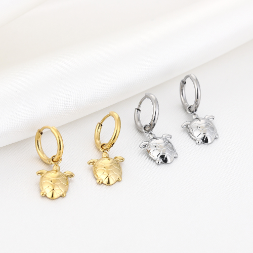 Set goudkleurige en zilverkleurige oorringen met schildpadbedels – maritieme sieraden met gedetailleerd design op witte achtergrond.
