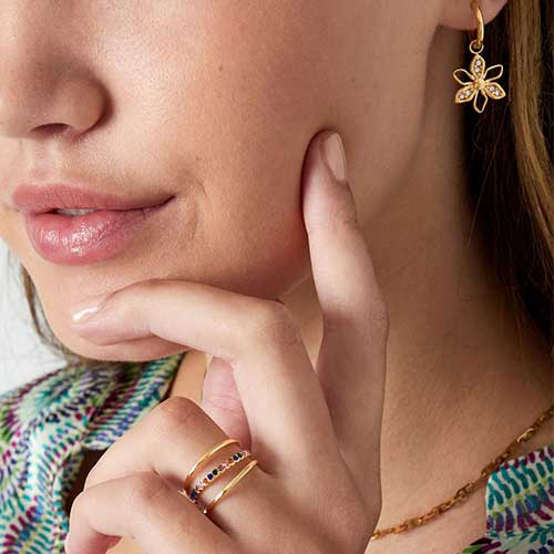 Luxe drie-laagse goudkleurige RVS ring met diagonale middelste band bezet met diverse gekleurde crystal steentjes, elegant ontwerp.