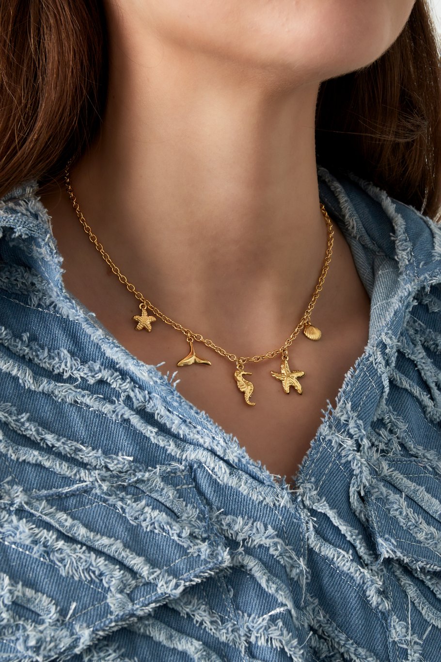 Goudkleurige RVS bedelketting met nautisch thema door de bedel van het zeepaardje, de staartvin, de zeester en de schelpen.