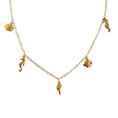 Goudkleurige ketting met zeepaardje, schelp en spiraalschelp bedels op witte achtergrond.