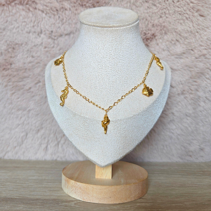 Gouden zeethema ketting met bedels, gepresenteerd op een display standaard.