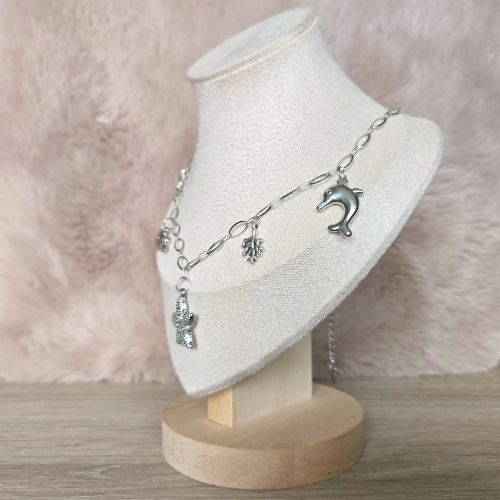 Zijaanzicht van zilverkleurige handgemaakte ketting met zeester, dolfijn en koraalbedels, perfect voor een maritieme look.