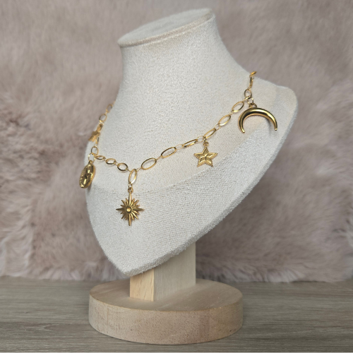 Gouden ketting met maan, zon en sterren bedels – zijaanzicht op beige sieradenbuste voor stijlvolle presentatie.