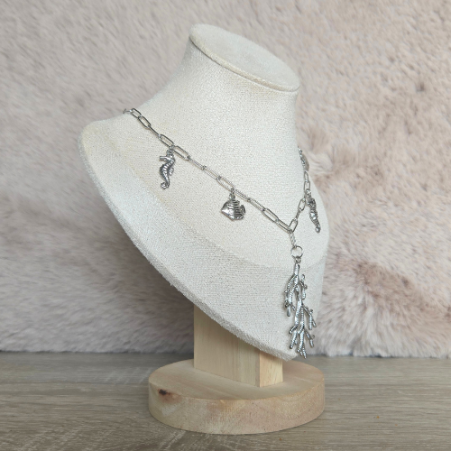Handgemaakte zilveren ketting met maritieme bedels gefotografeerd onder een hoek op display.