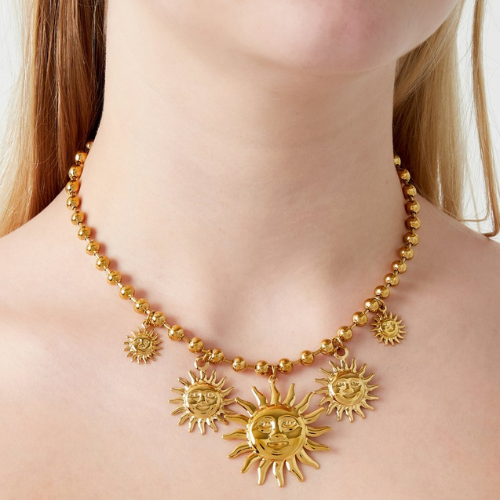 Goudkleurige bolletjes bedelketting met diverse zonnebedels en een grote statement hanger in het midden gedragen om de hals 