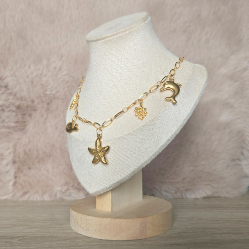 Goudkleurige handgemaakte stainless steel ketting met maritieme bedels op een fluwelen sieradendisplay.