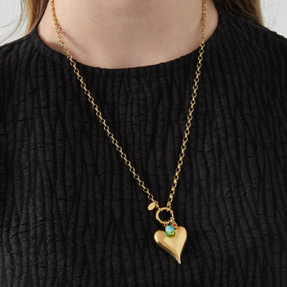 Goudkleurige Brielle Ketting met grote hartvormige hanger, turquoise kraal en roodkleurig detail - van roestvrijstaal - gedragen om de hals