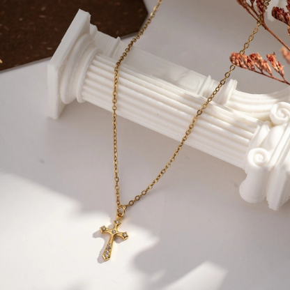 Goudkleurige ketting met kleine subtiele kruishanger ingelegd met zirkonia steentjes hangend neergelegd