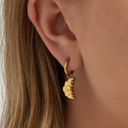 Close-up van oor met de goudkleurige croissant oorbel - gemaakt van hoogwaardig stainless steel
