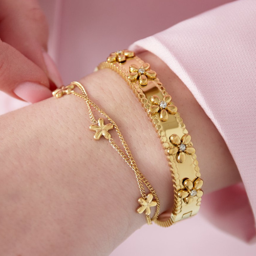 Goudkleurige roestvrijstalen armband met dubbele ketting en kleine madelief bedels gecombineerd met een bangle – gemaakt van roestvrijstaal