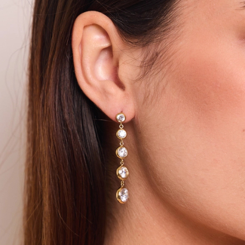 Luxe goudkleurige oorknopjes met geschakelde zirkonia stenen gedragen in het oor