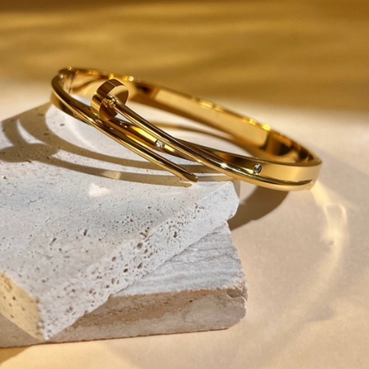 Goudkleurige spijkervormige gesloten bangle met zirkonia steentjes in het zonlicht