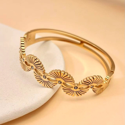 Gouden Eternal Rays Bangle met fonkelende zirkonia steentjes op een versierde ondergrond