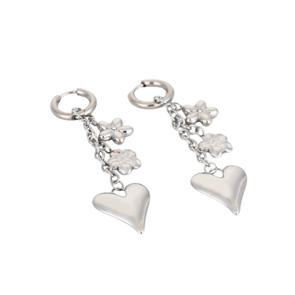 Set zilverkleurige Floralove oorbellen liggend weergegeven – romantische sieraden met bloemdetails en glanzende harten.