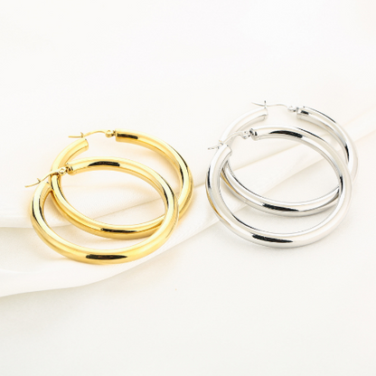 Goud- en zilverkleurige stainless steel hoops van vijf centimeter - liggend op een doek