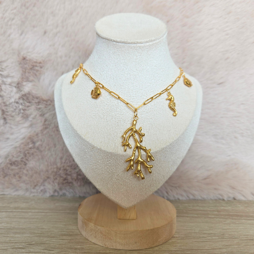 Vooraanzicht van een gouden koraalketting met maritieme bedels op display tegen een neutrale achtergrond.