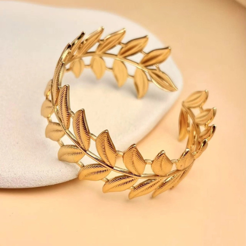 Een goudkleurige verstelbare bangle van stainless steel in de vorm van een tak met bladeren 