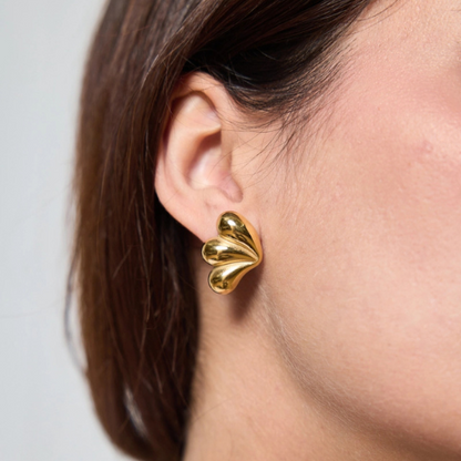 Goudkleurige golvende dames oorbellen gedragen in het oor