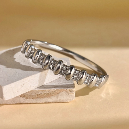 Zilverkleurige gesloten bangle ingelegd met zirkonia in het zonlicht