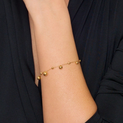 Goudkleurige bolletjes armband gedragen om de pols