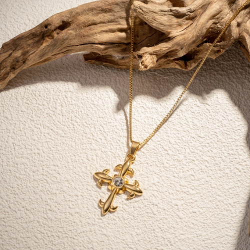 Goudkleurige kruis ketting met zirkonia steen in het zonlicht