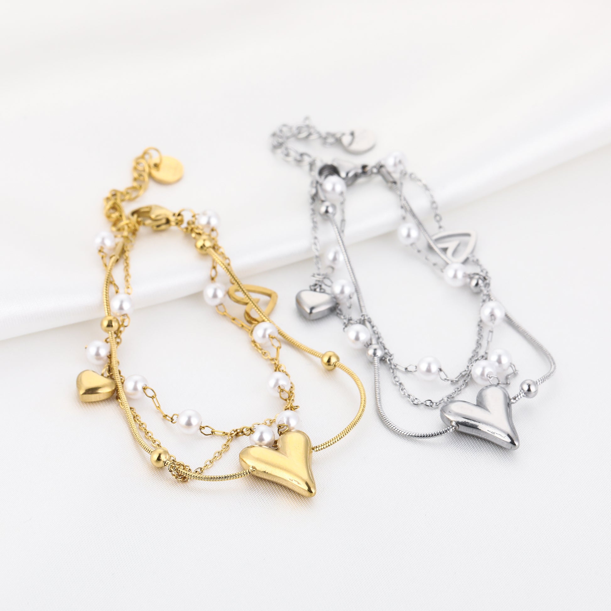 Zilver- en goudkleurige Pearl Love Armband met hartjes en parels - van roestvrij staal - gelegen op een platte ondergrond