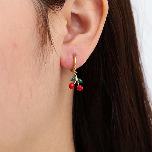 Goudkleurige red cherry oorbellen met rode kersen en groene blaadjes – speelse oorbellen met fruit design in het oor