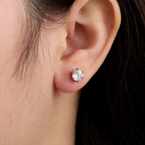 Goudkleurige Studs ingelegd met fonkelende zirkonia stenen gedragen in het oor - gemaakt van stainless steel