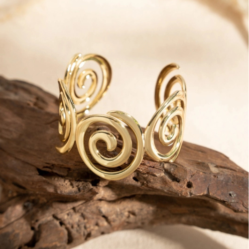 Goudkleurige open bangle in spiraalvorm in het zonlicht