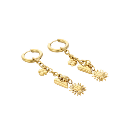 Set goudkleurige Sunnyheart oorbellen liggend weergegeven – speelse sieraden met symbolische zon-, hart- en bloembedels.