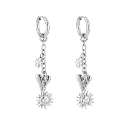 Zilverkleurige Sunnyheart oorbellen met hangende zon-, hart- en bloembedels – symbolische statement oorbellen van roestvrij staal.