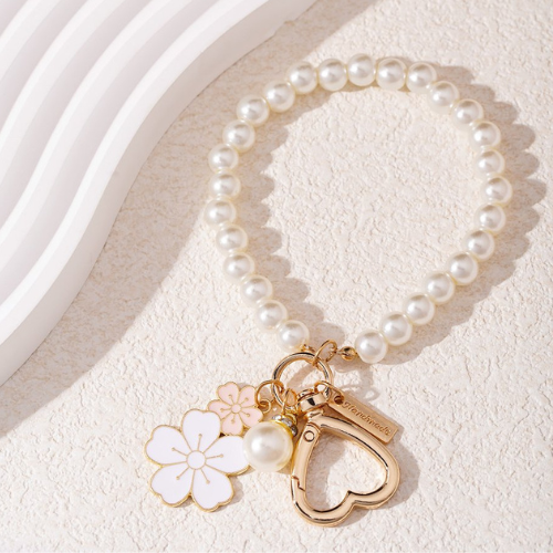 Tassenhanger met parels en witte en roze bloem in het zonlicht