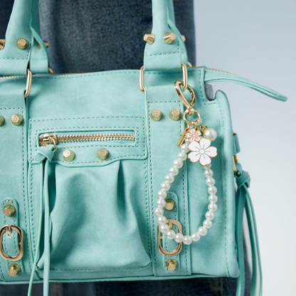 Tassenhanger met parels en witte en roze bloem aan een mintgroene tas