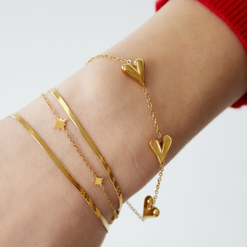 Goudkleurige armband met drie hartjes – van roestvrij staal - gecombineerd met andere minimalistische armbanden
