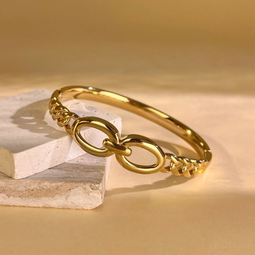 Goudkleurige gesloten bangle met gedraaide structuur in het zonlicht