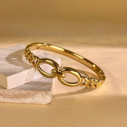 Goudkleurige gesloten bangle met gedraaide structuur in het zonlicht