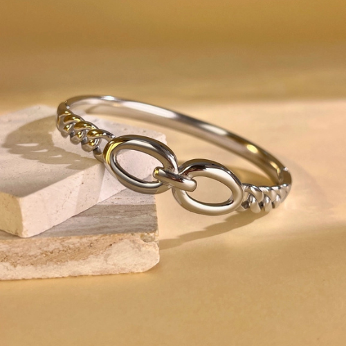 Zilverkleurige gesloten bangle met gedraaide structuur in het zonlicht