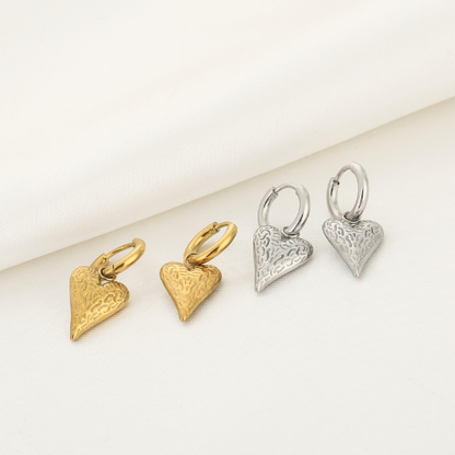 Set goud- en zilverkleurige Wildheart oorbellen liggend weergegeven – unieke hartvormige sieraden met speels textuurpatroon.