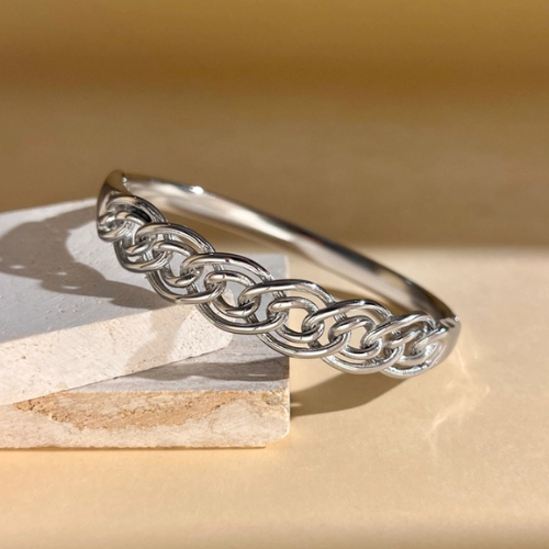 Zilverkleurige gesloten bangle met geweven patroon in het zonlicht